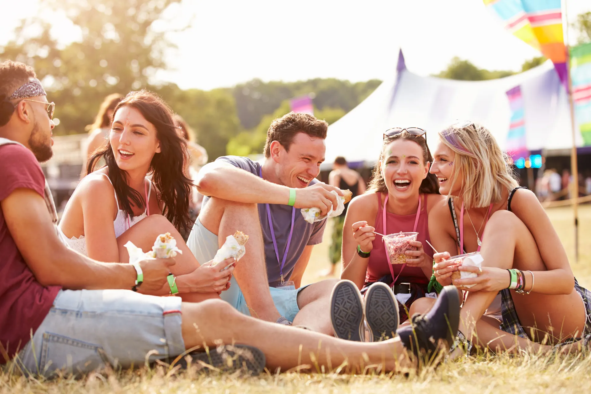 Friends sharing food on the grass at an outdoor festival
